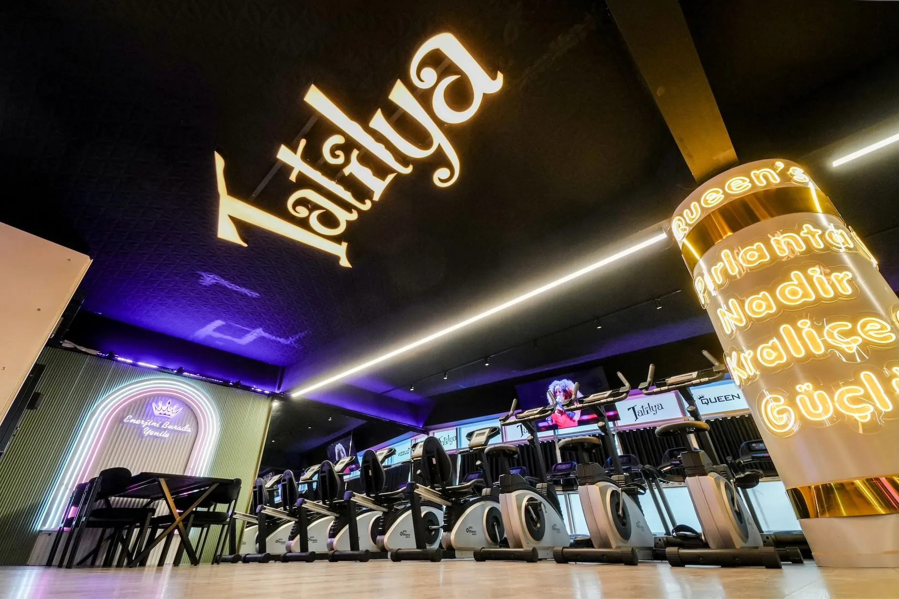 Altın Tatilya yazısı altında neon ışıklı cardio alanı